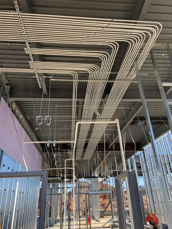 Rows of bent EMT conduit racked across a commercial building ceiling in Gillette, Wyoming