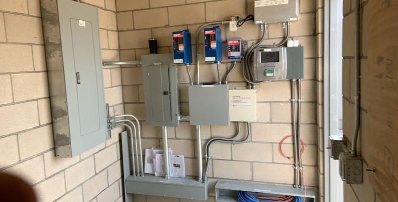 Wide view of a commercial equipment room with multiple electrical panels and breakers